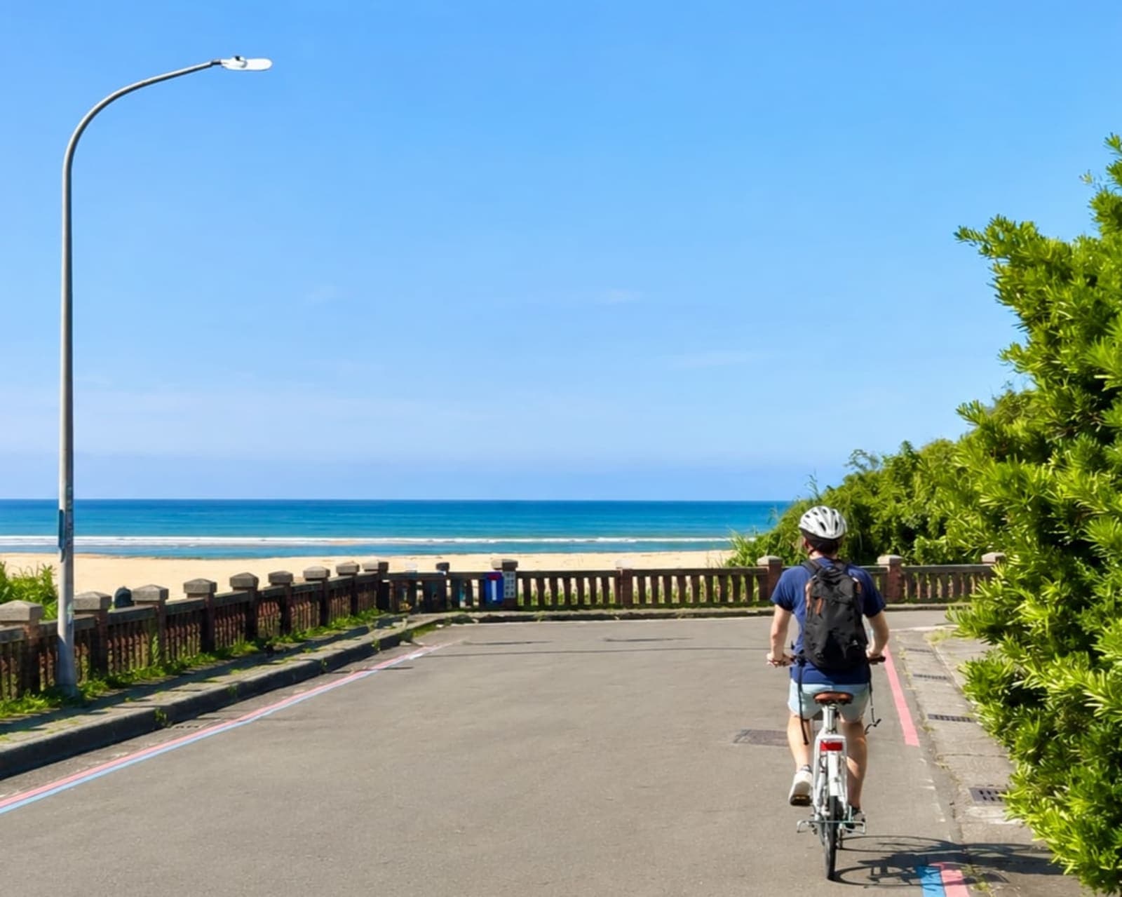 騎單車行經濱海步道，前方是金色沙灘與湛藍海洋
